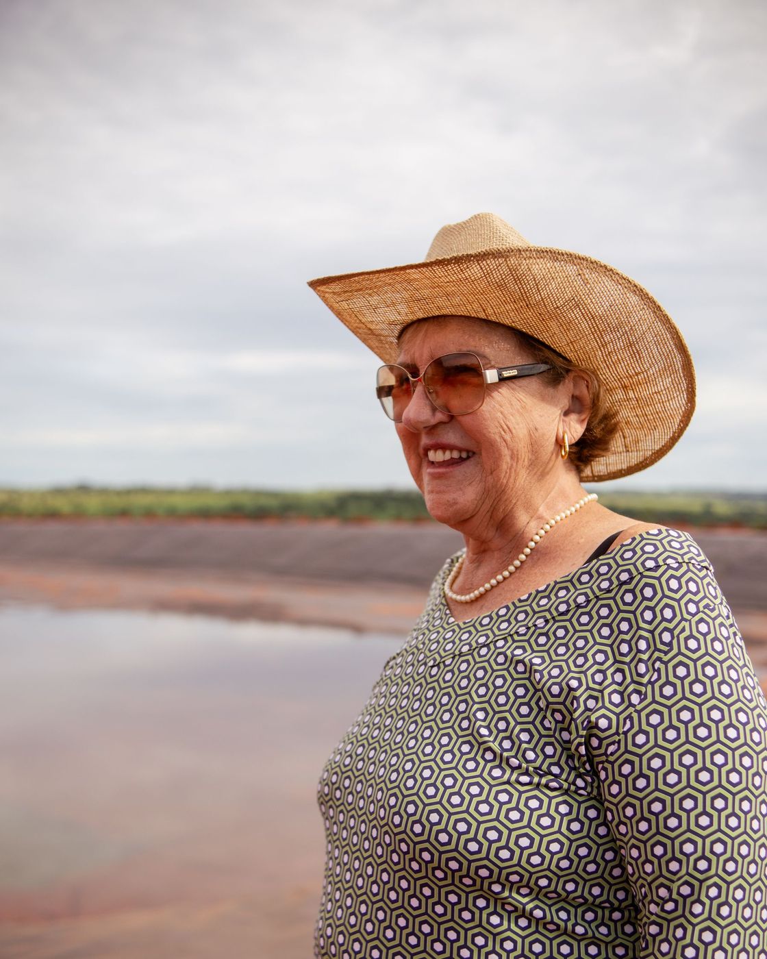 Senhora de chapéu sorrindo, no campo